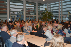 Interessierte sitzen im großen Sitzungssaal
