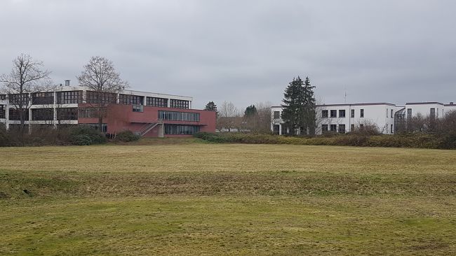 Bauplatz für den Kindergarten Neubau. Im Hintergrund sieht man das Gymnasium